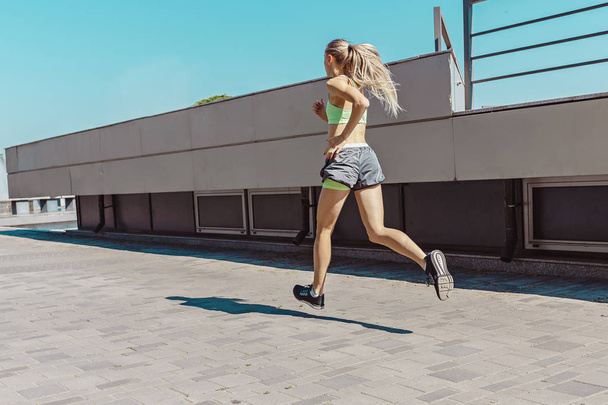 Pretty sporty woman jogging at city - Foto, afbeelding