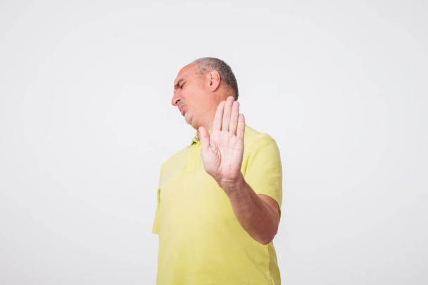Starší muž v žluté tričko ukazující znamení zastavit rukou. Odepřít něco udělat - Fotografie, Obrázek