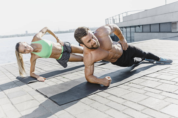 Fit fitness woman and man doing fitness exercises outdoors at city - Foto, Bild
