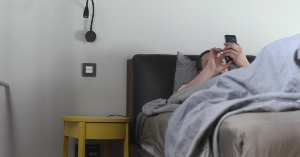 Man using mobile phone in bed - Záběry, video