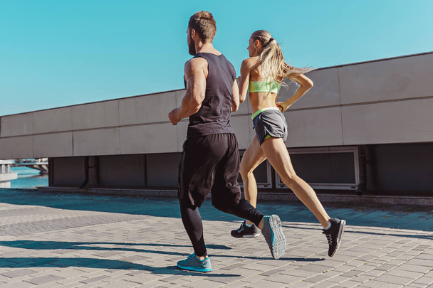 Pretty sporty woman and man jogging at city - Фото, зображення