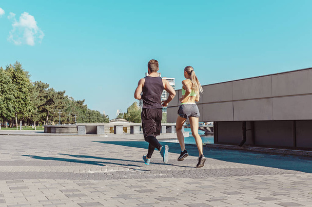 Pretty sporty woman and man jogging at city - Фото, изображение
