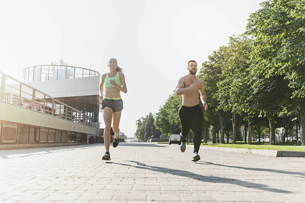 Pretty sporty woman and man jogging at city - Photo, Image