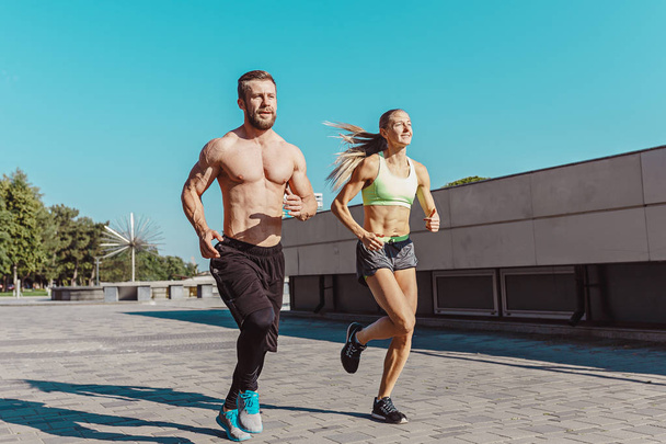Pretty sporty woman and man jogging at city - Photo, image