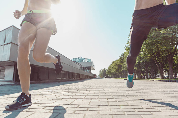 Pretty sporty woman and man jogging at city - 写真・画像