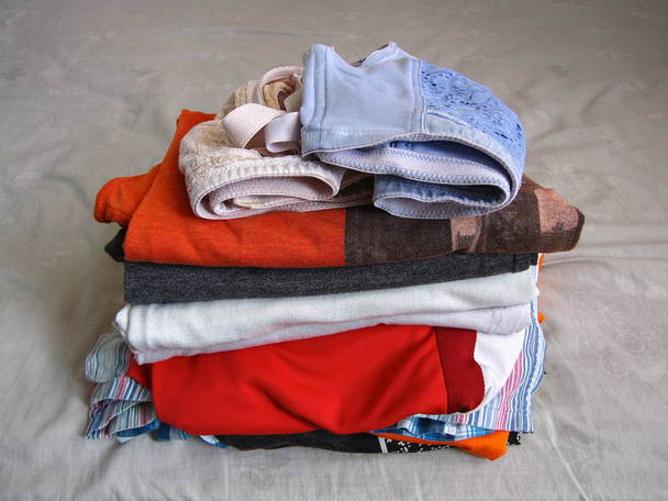 Montón de ropa y sujetador en la cama
 - Foto, imagen