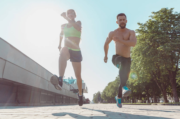 Pretty sporty woman and man jogging at city - Valokuva, kuva
