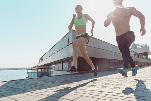 Pretty sporty woman and man jogging at city - Fotó, kép