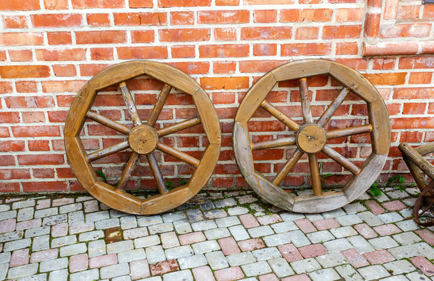 Старые деревянные колеса возле кирпичной стены
 - Фото, изображение