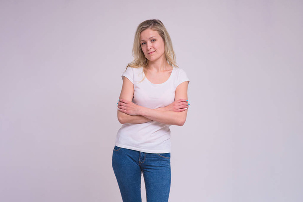 portrait of a beautiful blonde girl on a white background in different poses with different emotions. She is standing right in front of the camera smiling and looking happy - Photo, Image