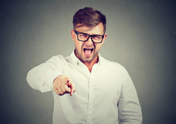 Casual man in glasses and white shirt pointing at camera and screaming in blame and accuse - Fotoğraf, Görsel