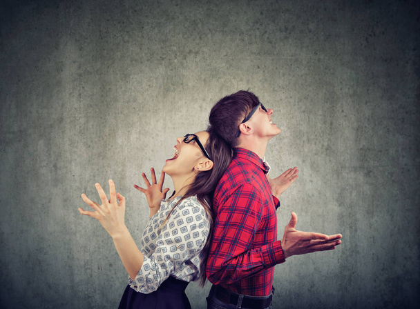 Side view of man and woman in glasses standing back to back screaming in frustration  - Foto, Imagem