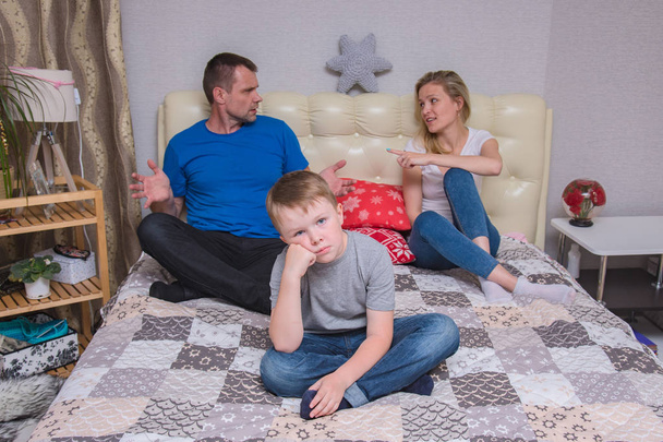 portrait of husband and wife and son aged 6 years in the room: family difficulties, problems, family relationships. They sit in front of the camera to quarrel and look unhappy - Photo, Image