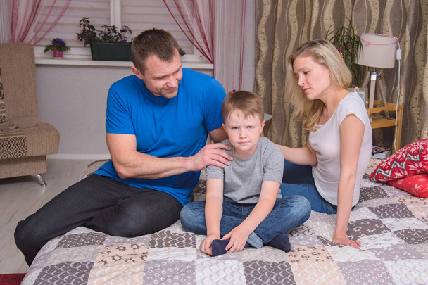 portrait of husband and wife and son aged 6 years in the room: family difficulties, problems, family relationships. They sit in front of the camera to quarrel and look unhappy - Foto, Imagen