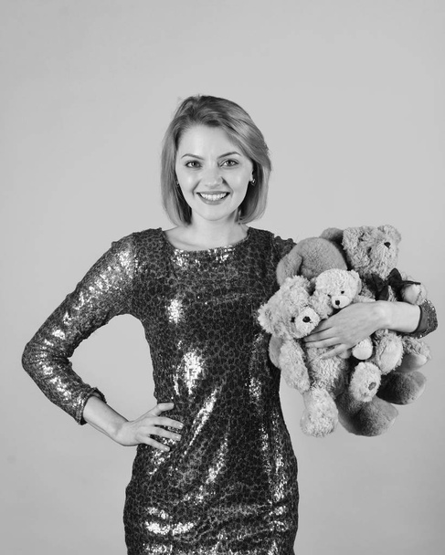 Woman holds heap of teddy bears on blue background. Lady with blond hair hugs cute toy bears. - Fotó, kép
