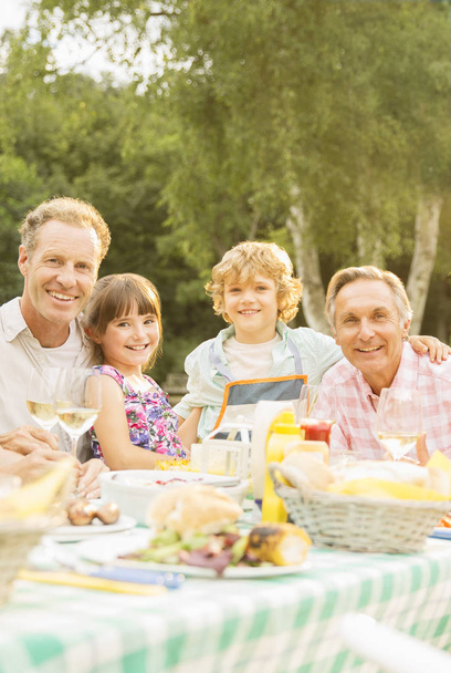 Família de várias gerações almoçando à mesa no quintal
 - Foto, Imagem