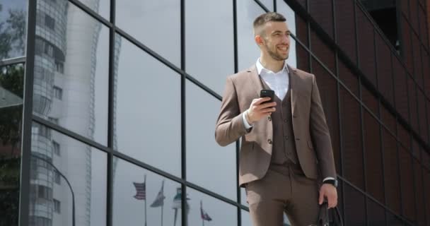 Businessman using his smart phone. Handsome young man communicating on smartphone smiling confident - Materiał filmowy, wideo