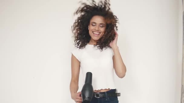 young curly-haired girl sings in a hair dryer and dances at home - Video, Çekim