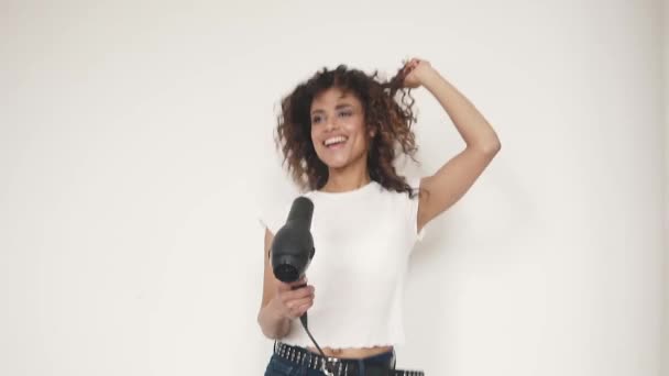 young curly-haired girl sings in a hair dryer and dances at home - Filmati, video