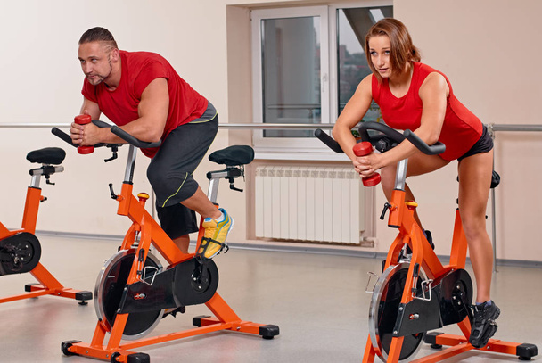 attractive couple bycicle cycling in gym - Photo, Image