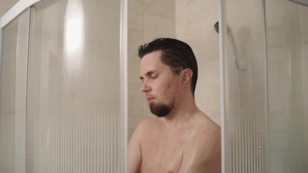 Szczupły mężczyzna jest spienianie jego ciało mydłem pod prysznicem, portret - Materiał filmowy, wideo