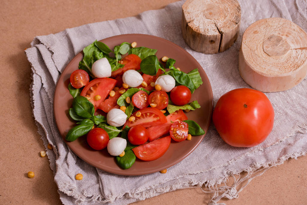 Traditional Italian fresh salad Caprese made of organic cherry tomatoes and mini mozzarella di Bufalla over a pheasant blue stone background. Healthy and traditional food concept. Top View. - 写真・画像