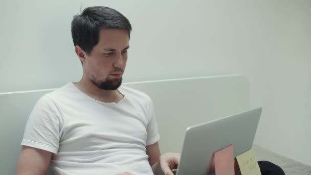 Cientista da computação está trabalhando em uma casa com laptop, sentado na cama
 - Filmagem, Vídeo