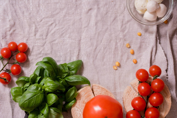 Caesar salad with white mozzarella cheese and cherry tomatoes, fresh basilon a gray linen napkin. wooden table, copy space. - Zdjęcie, obraz