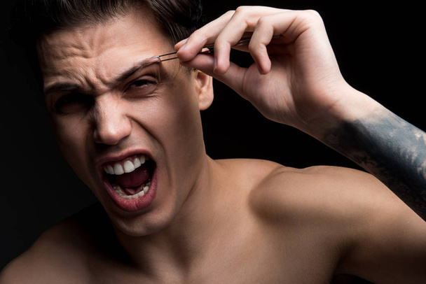 Young guy is plucking his eyebrows - Foto, Imagem
