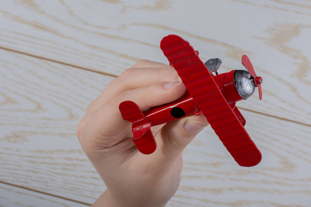 Рука тримає червону іграшкову площину на дерев'яній текстурі
 - Фото, зображення