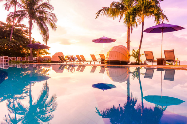 Belle vue extérieure avec parasol et chaise autour de la piscine dans un hôtel de luxe et station balnéaire au lever du soleil pour les voyages et les vacances
 - Photo, image