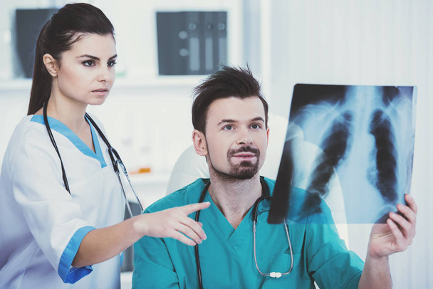 Doctor in green medical gown holds roentgen. - Photo, image