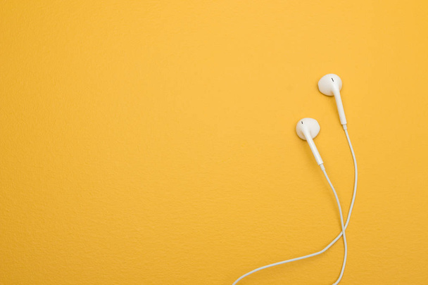White earphones on yellow background, with copy space on the left. - Photo, Image
