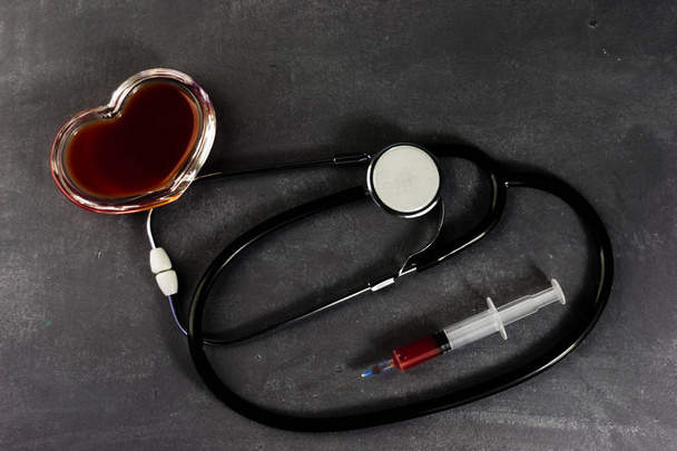 Piros szív és sztetoszkóp, barna asztal, egészségügyi világnap és egészségügyi koncepció. - Fotó, kép