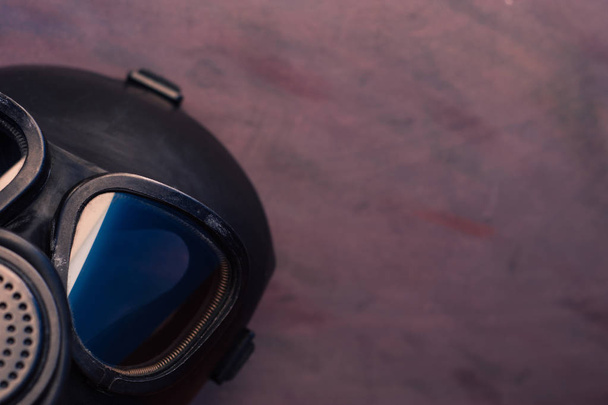 Μαύρη μάσκα αερίων με μπλε αντανάκλαση στο γυαλί σε ένα όμορφο φόντο. - Φωτογραφία, εικόνα