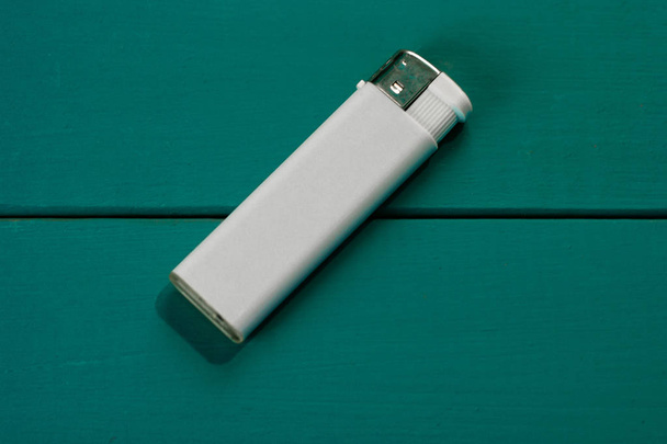Gasoline lighter , white plastic lighter on a blue wooden background - Photo, Image