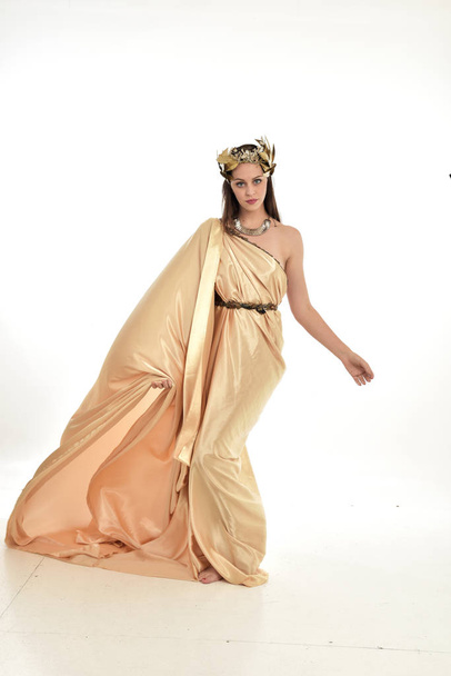retrato de longitud completa de la mujer morena con vestido de oro griego, de pie pose. aislado sobre fondo blanco del estudio
. - Foto, imagen