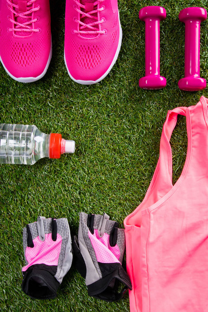pink sportswear, accessories and shoes, for fitness, a bottle of water, on the background of grass - Foto, Imagem