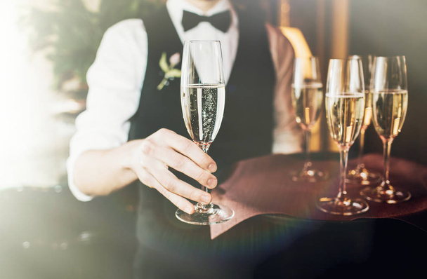 Waiter holding a dish of champagne glasses at some festive event, party or wedding reception - Foto, immagini