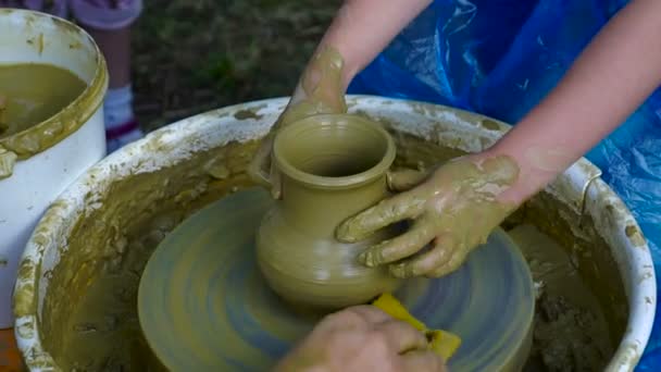 The potter's hands are shaped a cup from a clay. The process of creating pottery on a potter's wheel. The master ceramist teaches the pupil to make a pot in his studio. Close-up, only hands. - Footage, Video