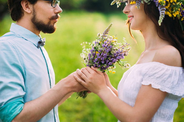 handsome guy with a beard in a blue denim shirt gives field flowers girl - Foto, imagen