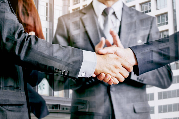 Händedruck von Geschäftspartnern vor dem Hintergrund eines Bürogebäudes - Doppelbelichtungsfoto - Foto, Bild