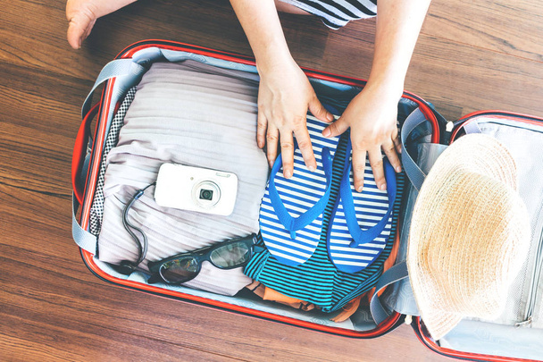 Woman packing a luggage on wooden floor - Photo, Image