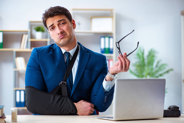 Businessman with broken arm working in office - Photo, Image