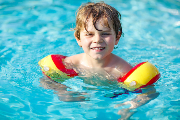 Szczęśliwy mały chłopiec dziecko zabawy w basenie. Active szczęśliwy przedszkola dziecko nauki pływania. z bezpiecznym floaties - Zdjęcie, obraz