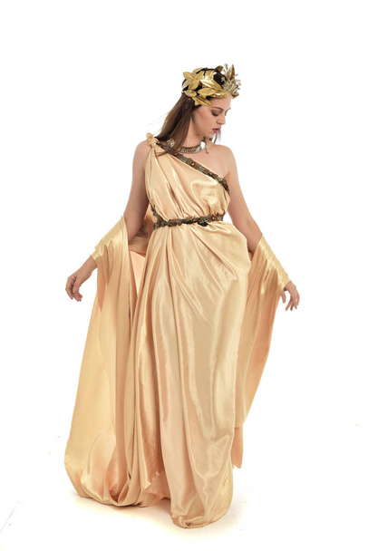 ritratto a figura intera di donna bruna vestita in oro grecian, in piedi posa. isolato su sfondo bianco dello studio
. - Foto, immagini