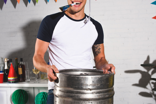 cropped shot of happy young man holding barrel of beer at home party - Photo, Image