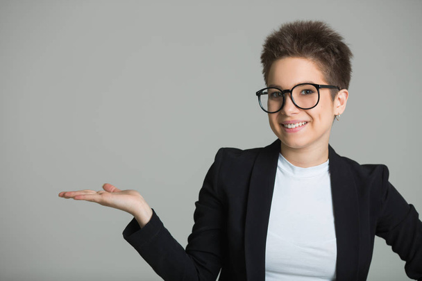 young beautiful girl with short hair on her head and with glasses with a short haircut on a gray background - Photo, Image