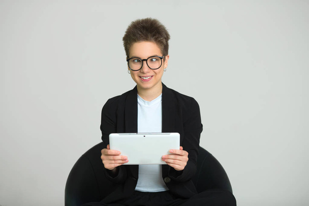young beautiful girl with short hair on her head, in a suit and glasses with a tablet in her hands with slanting eyes - Foto, imagen