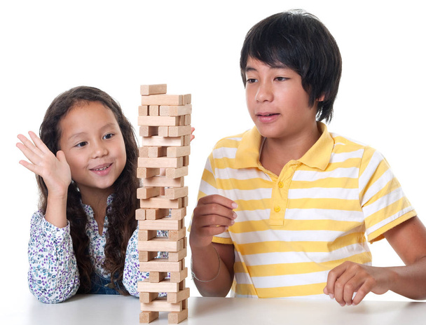 Дети играют и складывают башню из деревянных камней на белом фоне
 - Фото, изображение